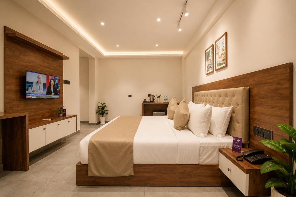 a hotel room with a bed and a television at Seaking Suites-MG Road in Cochin
