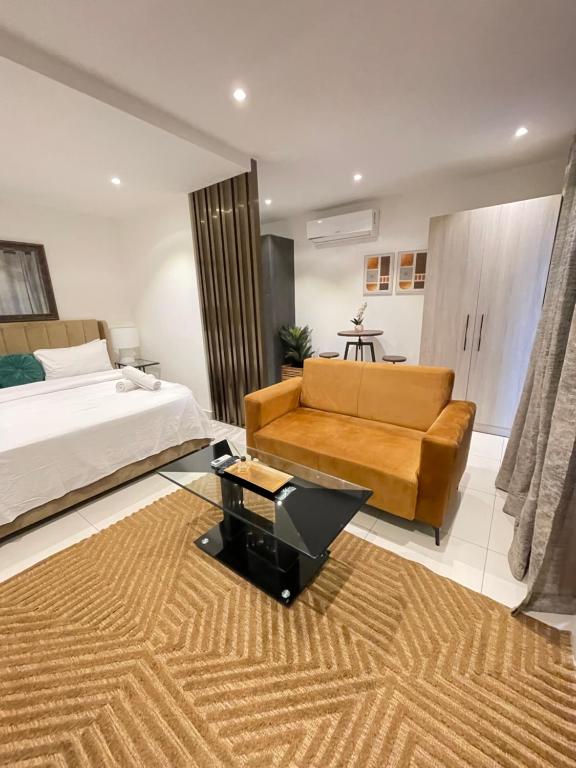 a bedroom with a bed and a couch and a table at Executive Suites at The Lennox in Accra