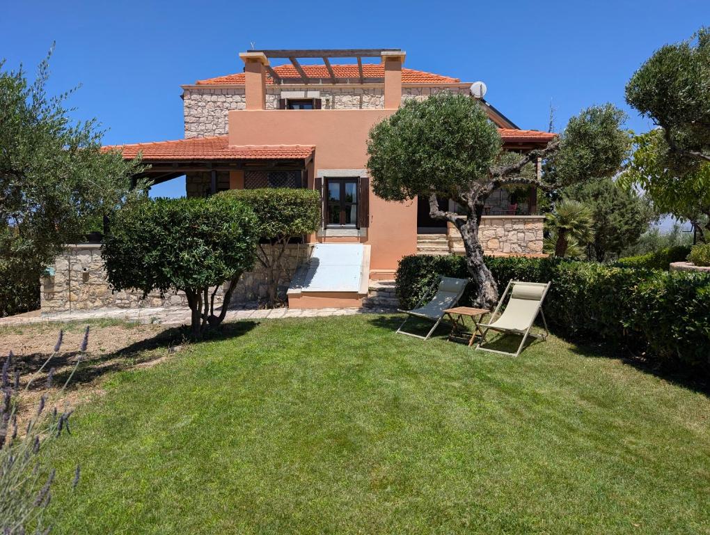 a house with two lawn chairs in the yard at Fyllosia Villa Part of Cretan Retreat in Archanes