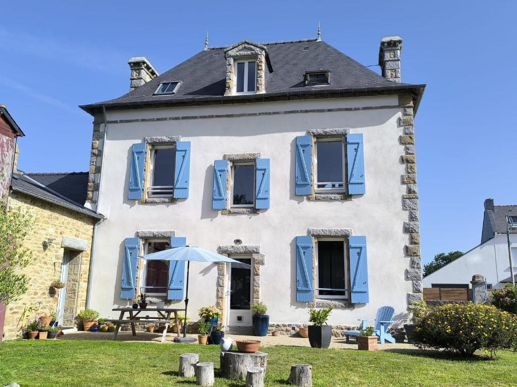 a large white house with blue shutters at Ty Maen - Étage avec chambre, coin salon, toilettes et salle de bain in Erdeven
