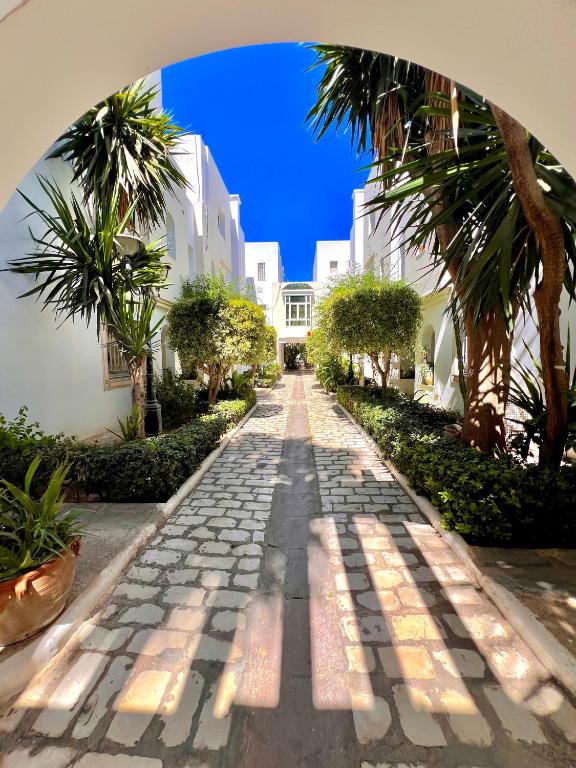 a cobblestone street with palm trees and a building at la Soukra in Sukrah