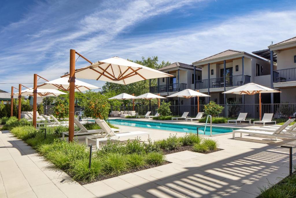 a swimming pool with umbrellas and lounge chairs next to a building at Duchamp Healdsburg in Healdsburg