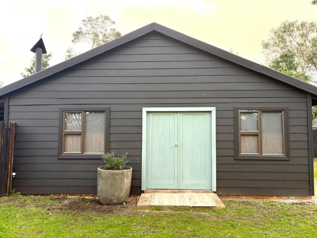 a black house with a blue door and windows at Raven in Stormsrivier