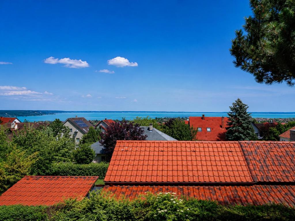 a view of roofs of houses and the ocean at Csendes Panoráma Apartman in Balatonalmádi