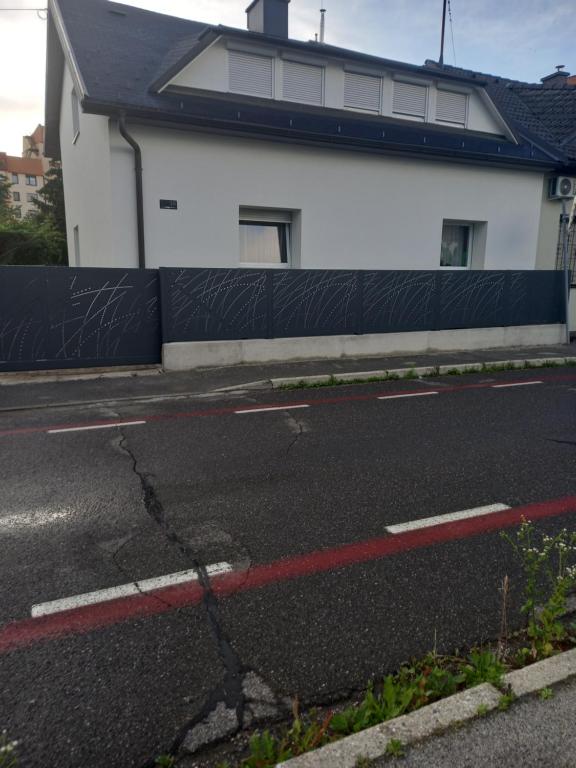 an empty street with a white building and a red curb at Apartment Zorec in Maribor