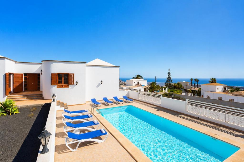 a villa with a swimming pool and blue chairs at Villa El Callao in La Asomada
