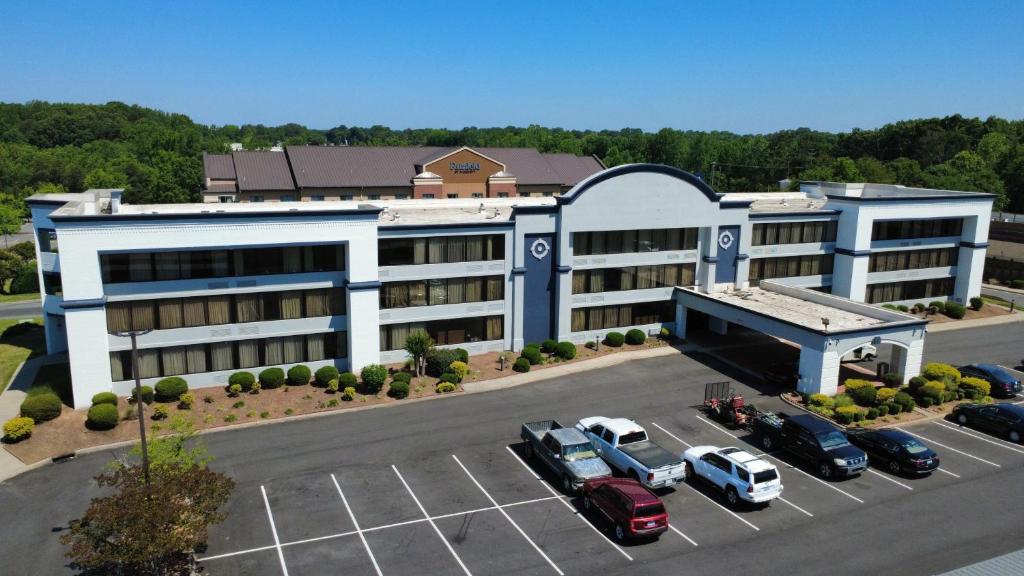 a large building with cars parked in a parking lot at SureStay by Best Western Charlotte Matthews in Matthews