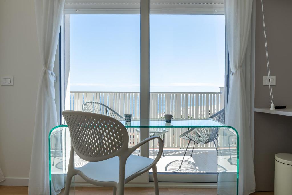 a glass table and a chair in front of a window at Palazzo Ambra in Soverato Marina