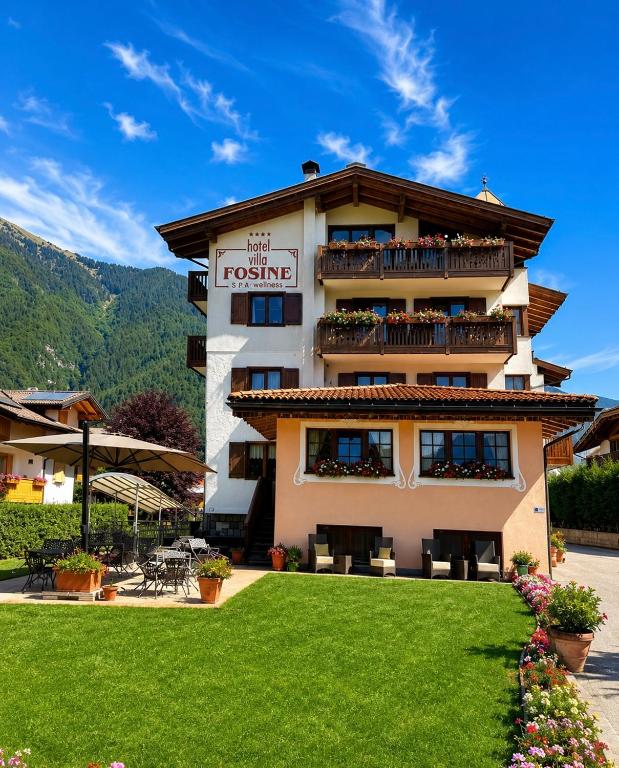a hotel with a green lawn in front of it at Hotel Villa Fosine Spa & Wellness in Pinzolo