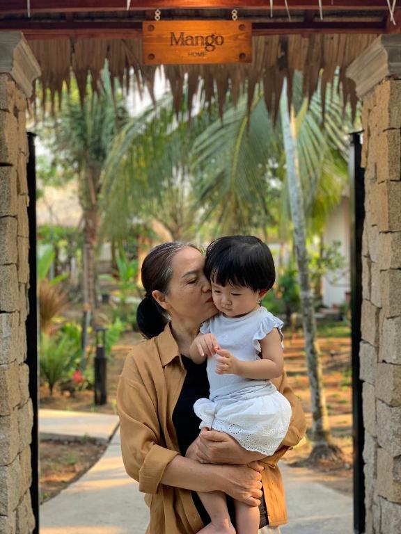 a woman is holding a child in her arms at Mango Home in Ben Tre