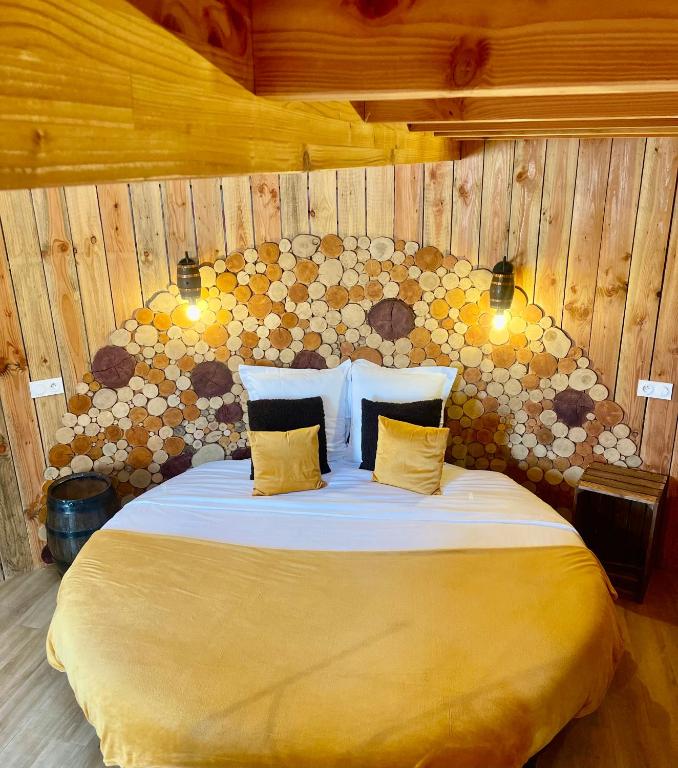 a bedroom with a large bed with a wooden wall at La Cabane Tonneau - Les Pieds dans le Pré in Les Landes-Génusson