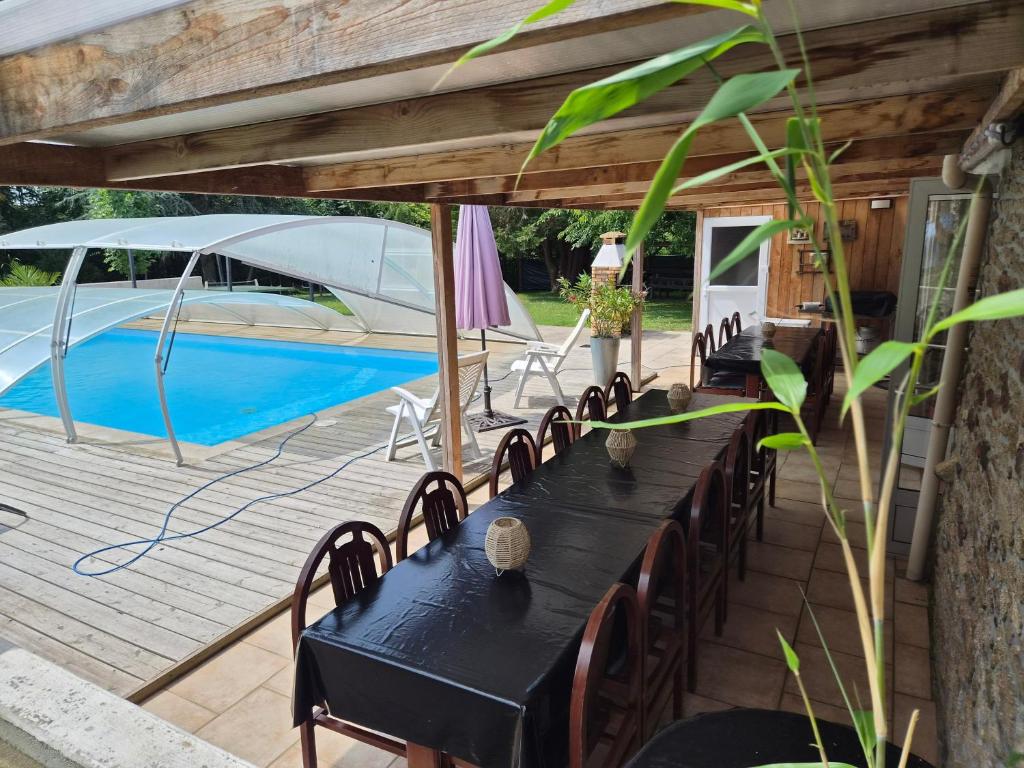 a black table and chairs on a patio with a pool at Gîte - Le Moulin Bernard - Béganne in Béganne
