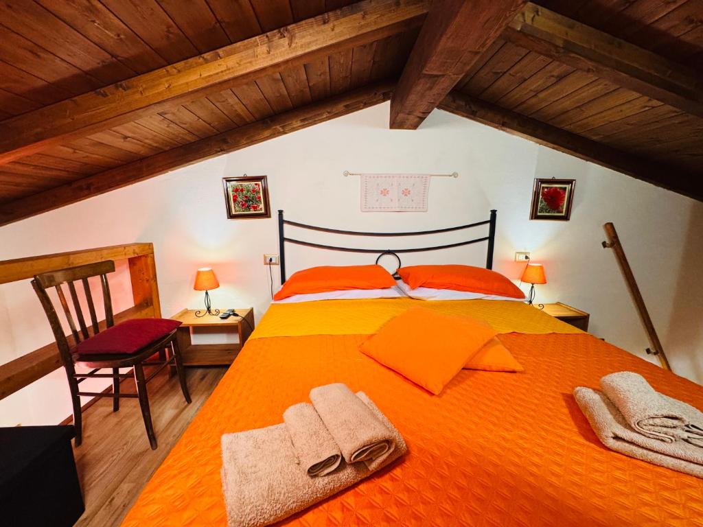 a bedroom with an orange bed with towels on it at Lilly's House in Monteponi