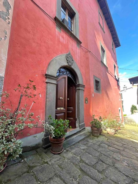 a red building with a door and some potted plants at La Torretta in Barga