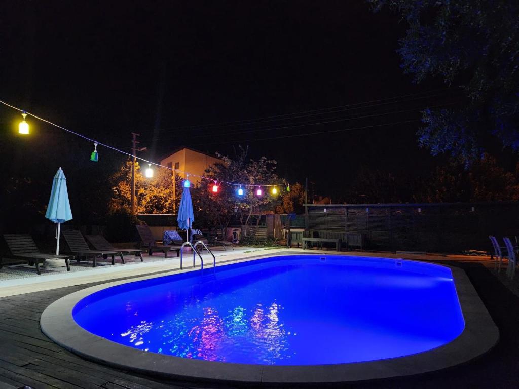 a blue swimming pool in a yard at night at Dardanos Pension in Hamidiye