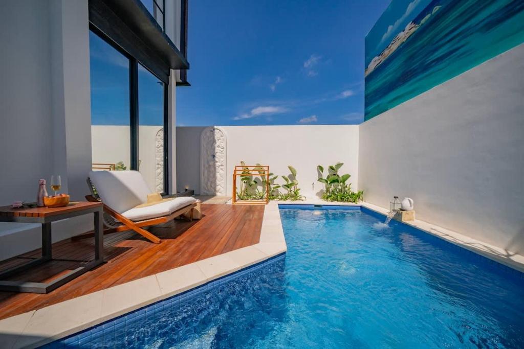 a pool with a chair and a table in a house at 2BR villa w - pool & beach access in Mengwi