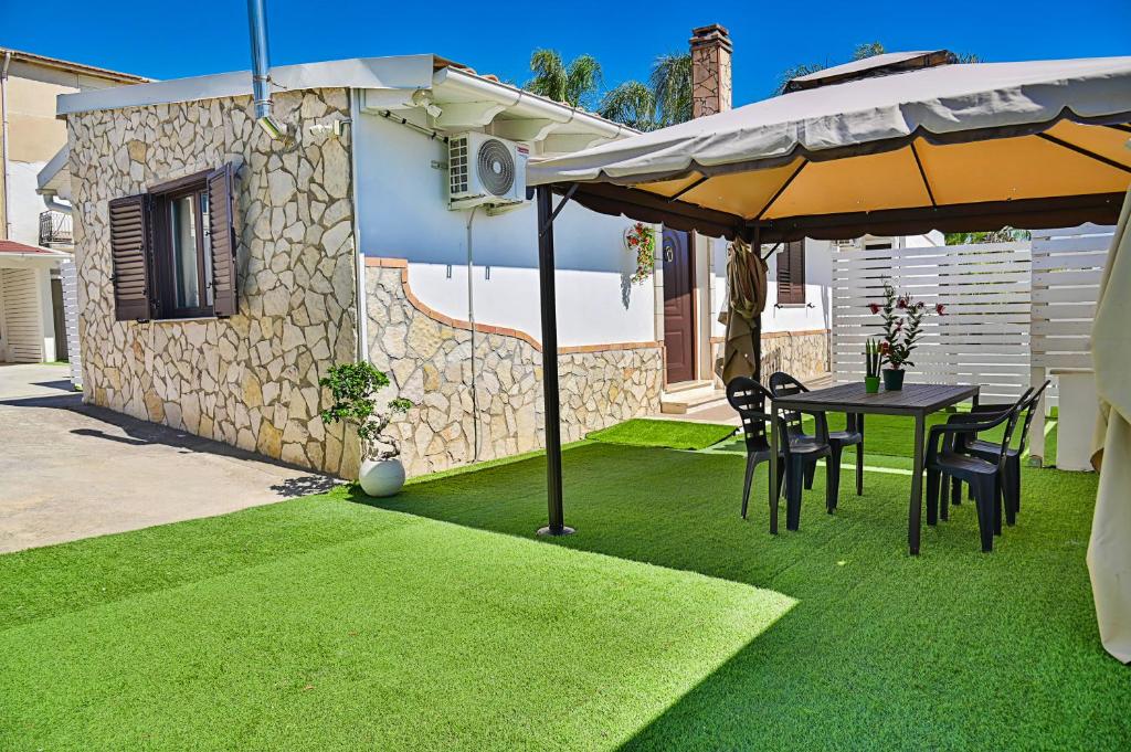a table and chairs under an umbrella on a lawn at Villa Mendolia in Villaggio Mosè