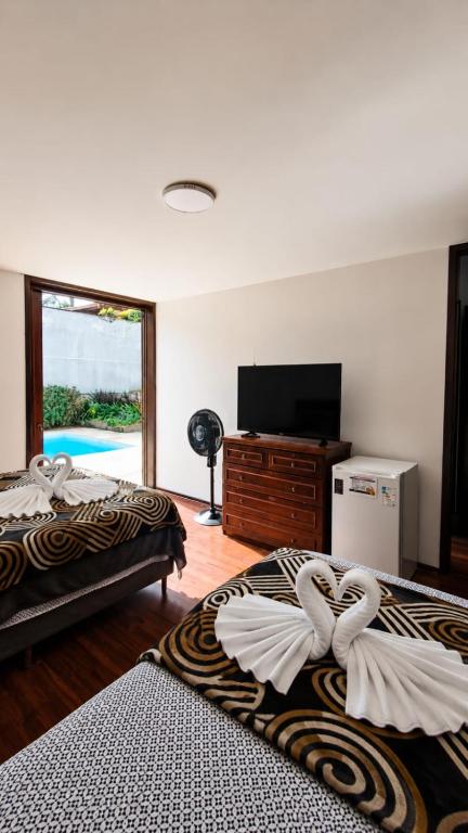 two beds in a room with a flat screen tv at Hospedagem Jardim Social,Quartos Econômicos e Suítes, Estacionamento Grátis in Curitiba