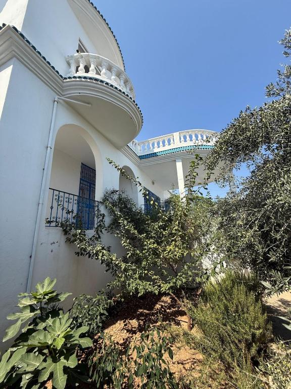 a white building with a balcony and some plants at Villa rafraf in Rafrāf