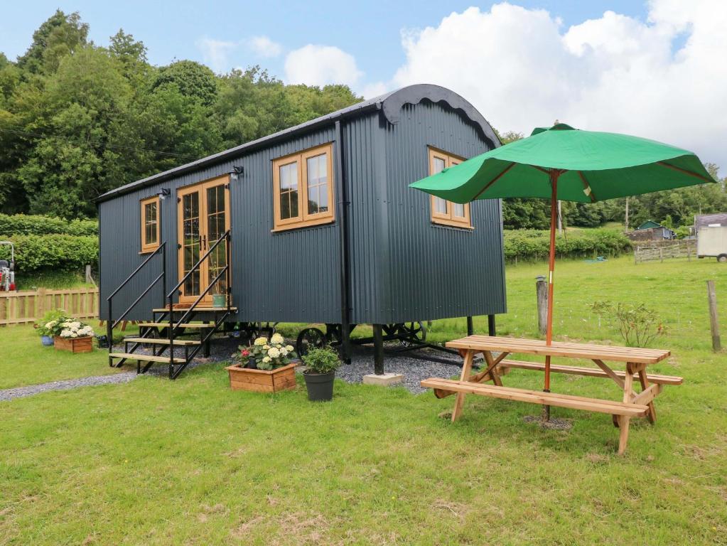 ein kleines Häuschen mit Picknicktisch und Sonnenschirm in der Unterkunft Cwtch Y Bugail 2 in Llandeilo