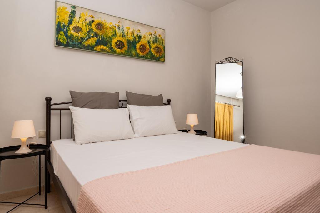 ein Schlafzimmer mit einem Bett und einem Gemälde an der Wand in der Unterkunft Marlen Luxury Studios & Apartments in Platamonas