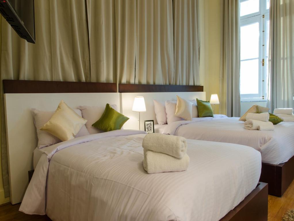 a bedroom with two beds with white sheets and green pillows at Grand Agor Hotel Cairo in Cairo