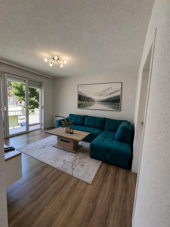 a living room with a blue couch and a table at Apartment Harmony Sarajevo Vogošća in Vogošća
