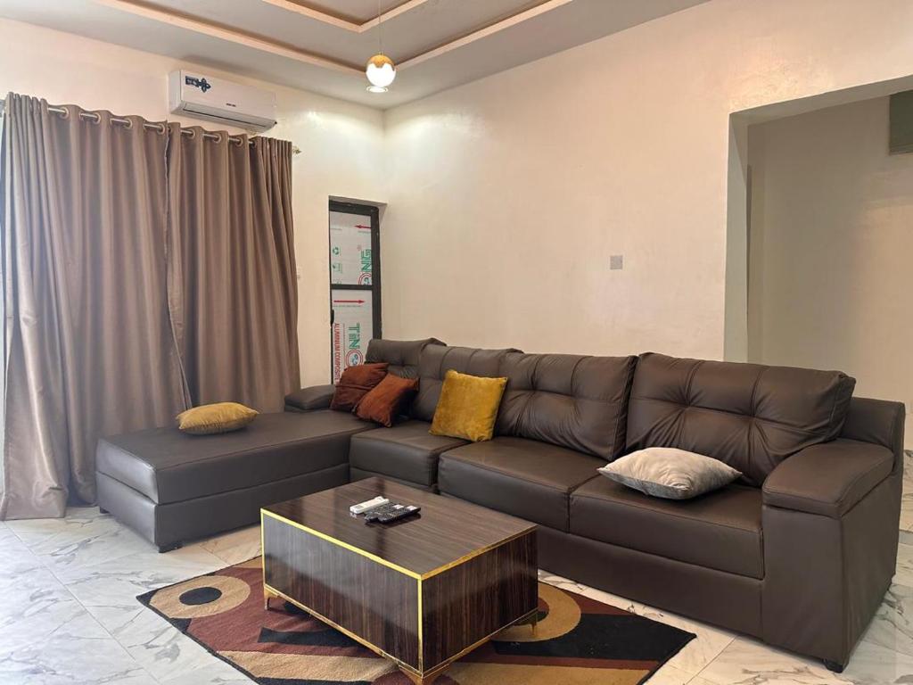 a living room with a leather couch and a coffee table at House 22 Apartments in Kubwa