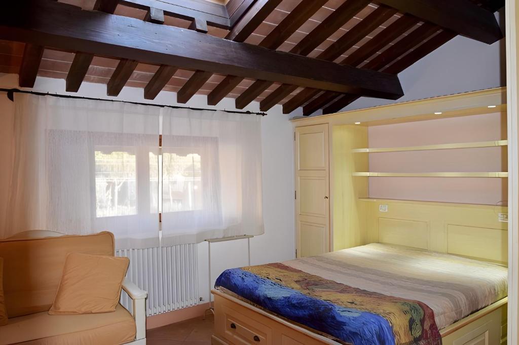 a bedroom with a bed and a chair and a window at Il Cantinone A due passi dal mare in San Vincenzo