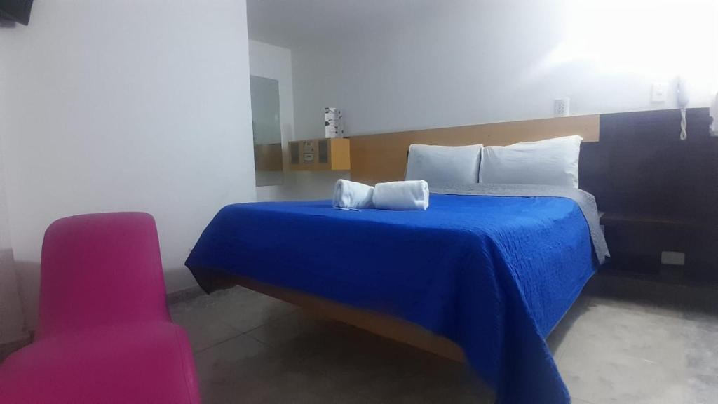 a bedroom with a blue bed and a pink chair at Hotel Bonaire Un Estilo Difrente in Bogotá