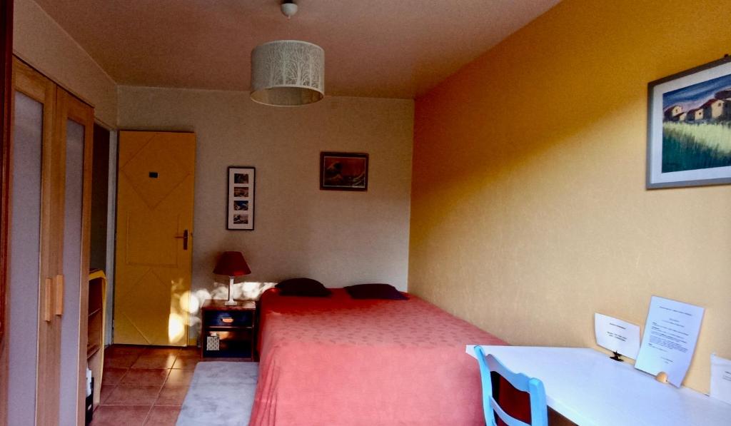 a bedroom with a red bed and a table at Chambre très calme in Montélimar
