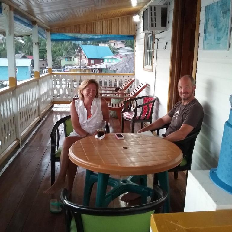 a man and a woman sitting at a table on a porch at Hotel Caribbean View in Bastimentos