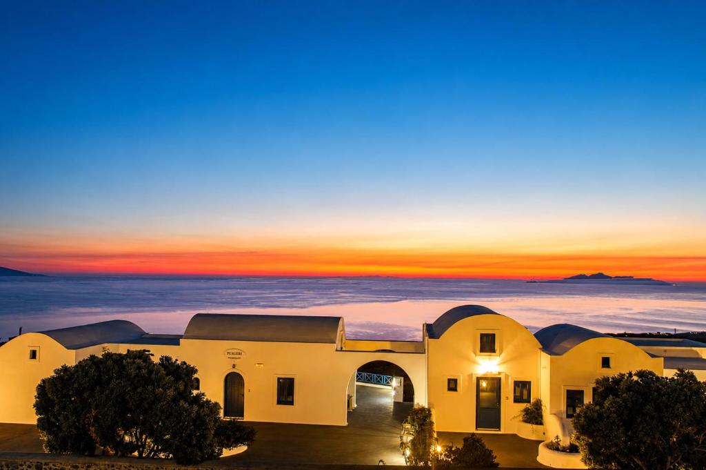 a building with a sunset in the background at Pergeri Apartments in Imerovigli