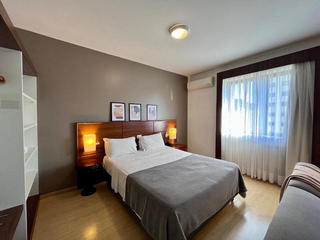 a bedroom with a large bed and a window at Studio apartment in downtown Joinville, SC in Joinville