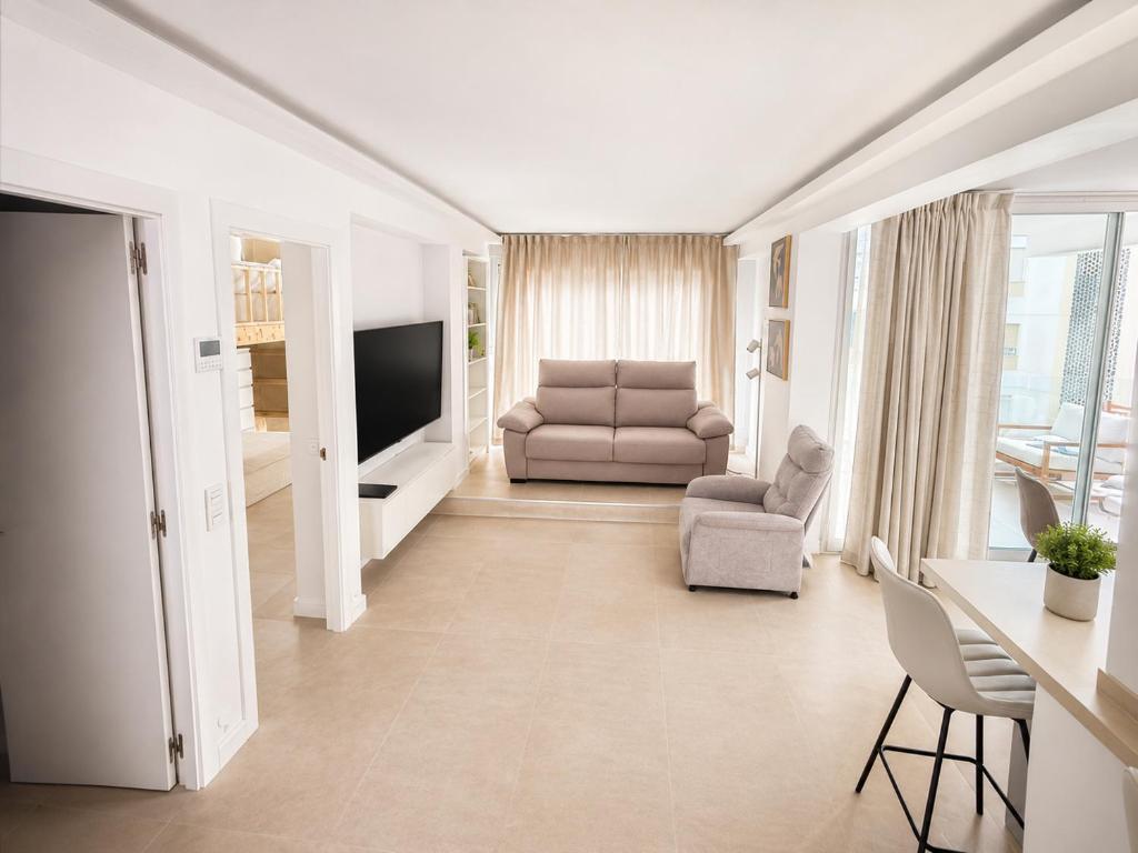 a living room with a couch and a chair and a television at Beach Apartment in Torre del Mar in Torre del Mar