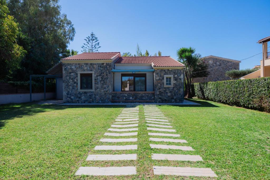 a house with a stone pathway in front of a yard at Villa Afroditi by Bostonia Village in Almiros Beach