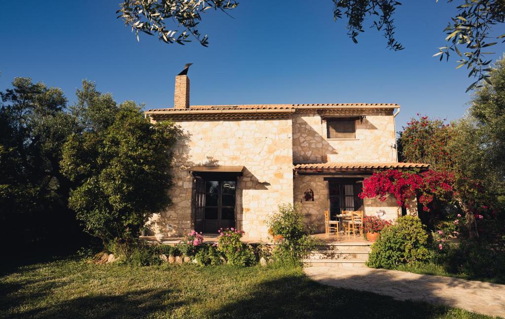 an old stone house in a yard with trees at Kidóni Villas in Gaïtánion