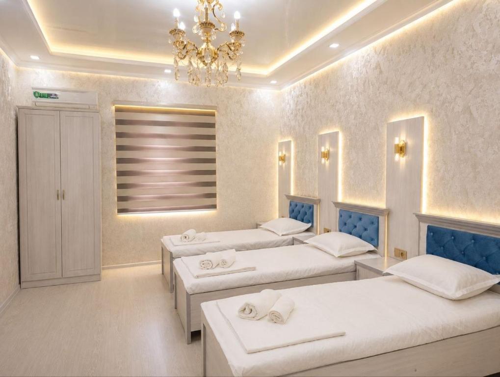 a room with three beds and a chandelier at comfort house in Khiva