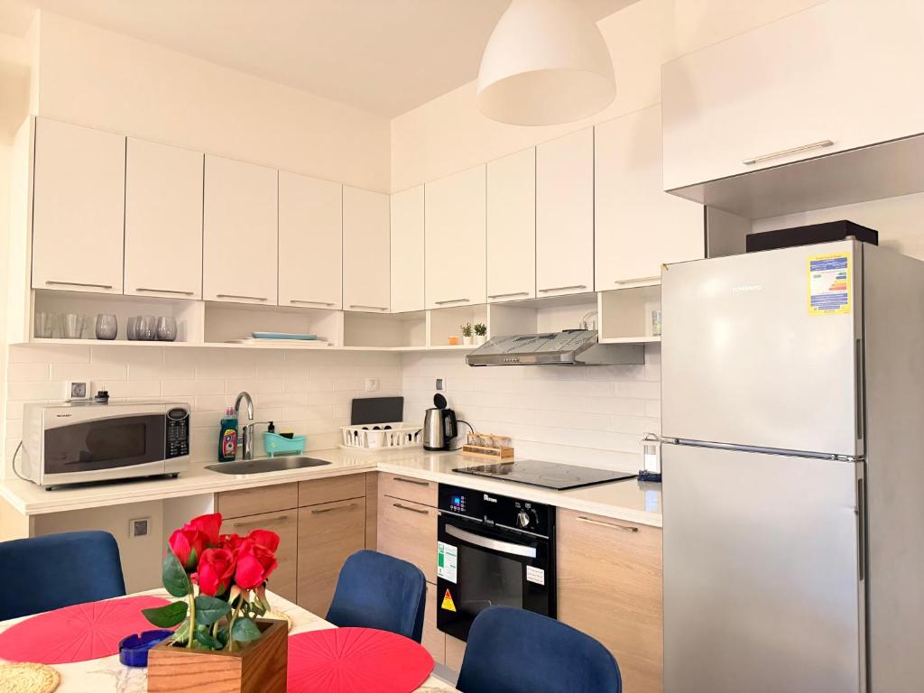 a kitchen with a white refrigerator and a table with red roses at Condo in Marassi Marina in El Alamein