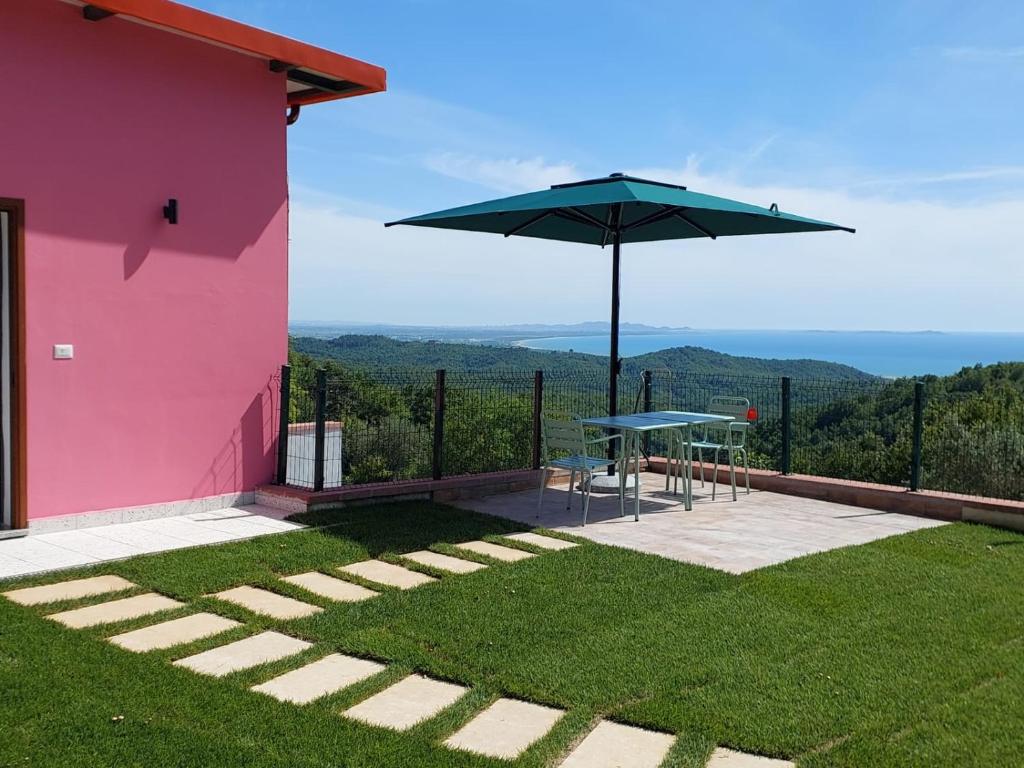 a pink house with a table and an umbrella at Villa Shtëpia në Pyll in Draç