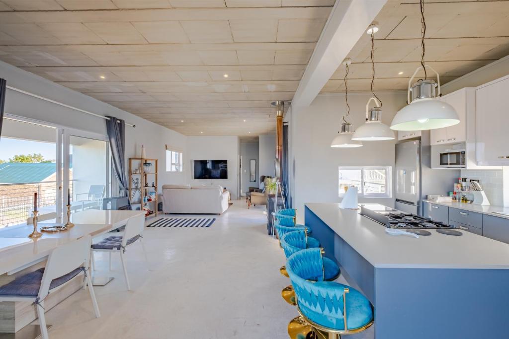 a kitchen with white counters and blue chairs at Meraki Sands in Hermanus