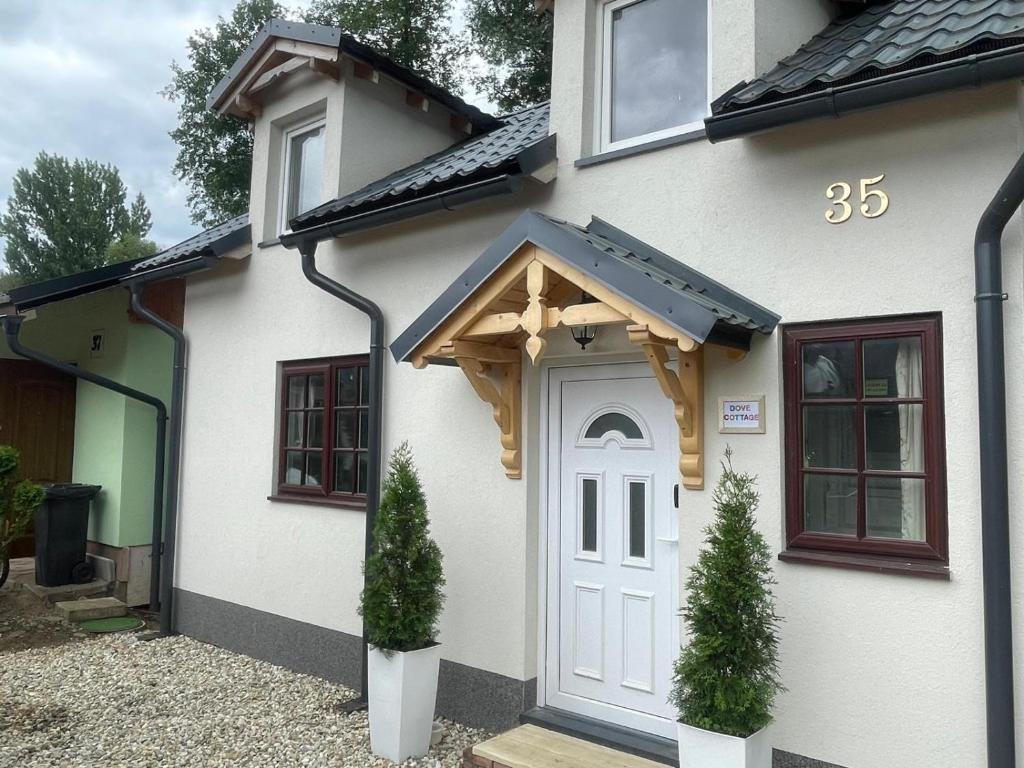 a white house with a white door with a wooden awning at Dove Cottage Chatka 35 Chalmová in Bystričany