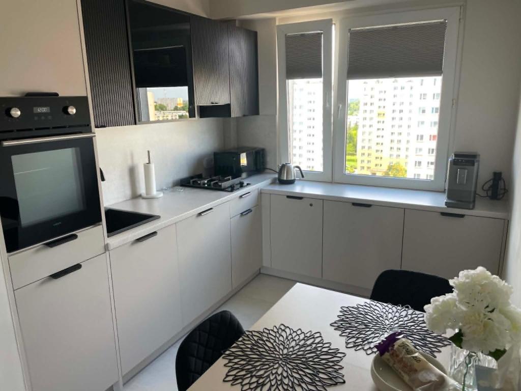 a kitchen with white cabinets and a table with a television at Apartament Rubinkowo in Toruń