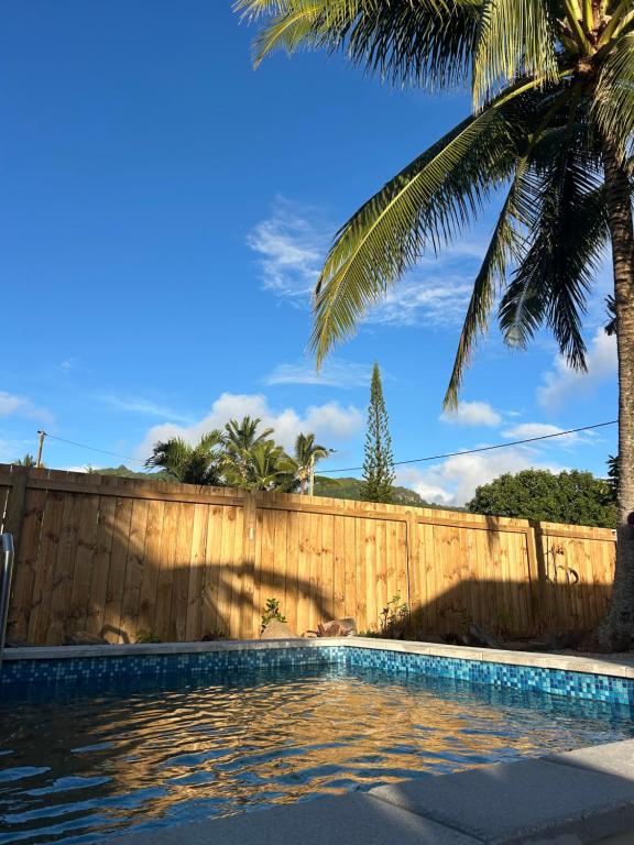 a swimming pool with a fence and a palm tree at Hildas Villa in Arorangi