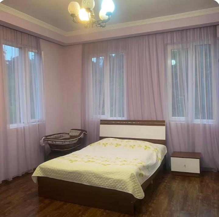 a bedroom with a bed and a chair and windows at Quiet house in Buknari