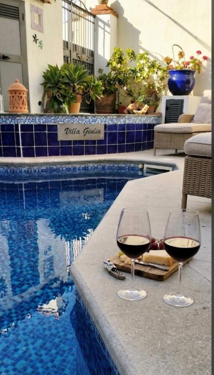 two glasses of wine sitting on a table next to a pool at Villa Giulia - Vesuvio Guest House Pompei Sorrento in Boscotrecase