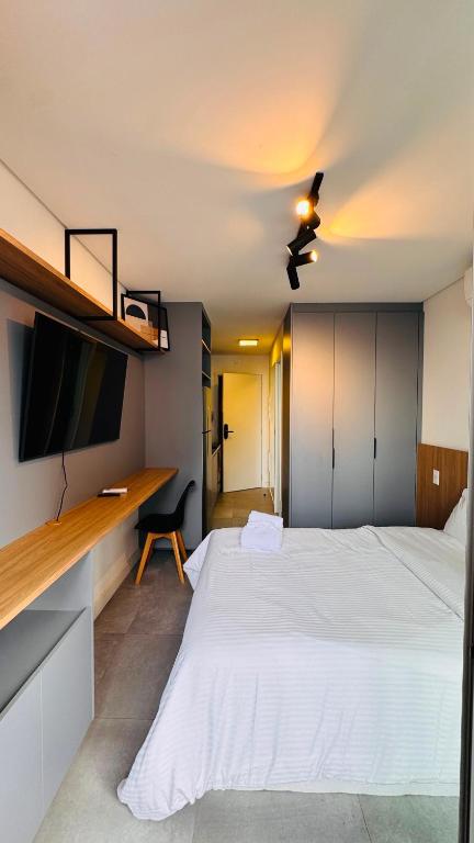 a bedroom with a large white bed and a tv at Almagah 227 - Studios de Alto Padrão no Tatuapé - SP in São Paulo