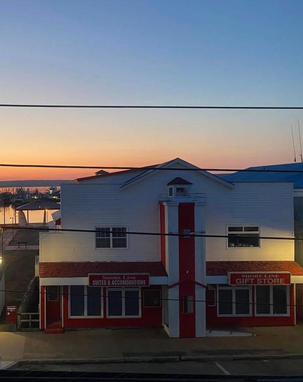 a white and red building with the sunset in the background at Shoreline Suites in Digby