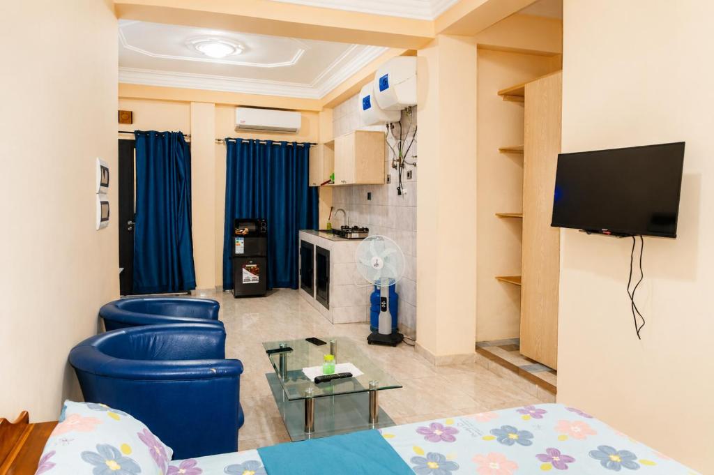 a living room with two blue stools and a tv at Résidence APOW in Agogoudjou