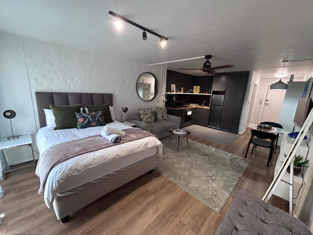 a bedroom with a bed and a living room at Greenpoint Chic Studio Apartment in Cape Town